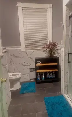 a bathroom with a toilet and two blue rugs at Big Mama's House in Paterson