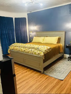 a bed in a bedroom with blue walls and wooden floors at Big Mama's House in Paterson