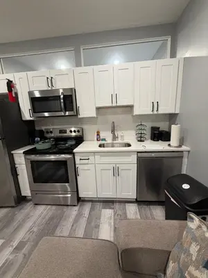 a kitchen with white cabinets and stainless steel appliances at Beautiful & Peaceful 1-Bedroom Suite in Philadelphia