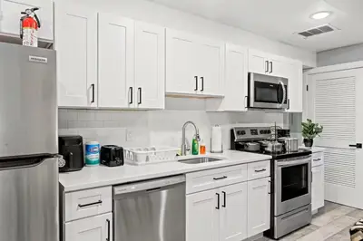 a kitchen with white cabinets and stainless steel appliances at Beautiful & Peaceful 1-Bedroom Suite in Philadelphia