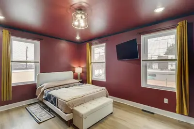 a bedroom with red walls and a bed and windows at Colorful and Convenient Darby Apt, 7 Mi to Stadiums! in Darby