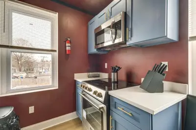 a kitchen with blue cabinets and a stove at Colorful and Convenient Darby Apt, 7 Mi to Stadiums! in Darby