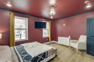 a bedroom with red walls and a bed and a chair at Colorful and Convenient Darby Apt, 7 Mi to Stadiums! in Darby