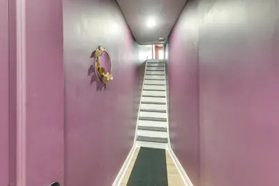 a hallway with a purple wall and a staircase at Colorful and Convenient Darby Apt, 7 Mi to Stadiums! in Darby