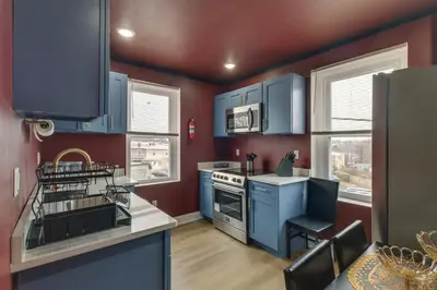 a kitchen with blue cabinets and a stove top oven at Colorful and Convenient Darby Apt, 7 Mi to Stadiums! in Darby