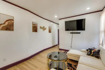 a living room with a couch and a tv on a wall at 7 Mi to Philly Stadiums! Charming Apartment in Darby