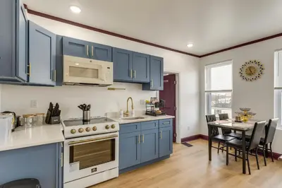 a kitchen with blue cabinets and a table with chairs at 7 Mi to Philly Stadiums! Charming Apartment in Darby