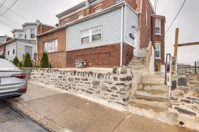a house with a stone wall in front of it at 7 Mi to Philly Stadiums! Charming Apartment in Darby