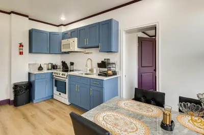a kitchen with blue cabinets and a table at 7 Mi to Philly Stadiums! Charming Apartment in Darby