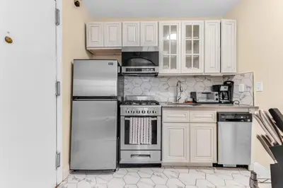 a kitchen with white cabinets and stainless steel appliances at Brooklyn Heights 2BR Secret Retreat in Brooklyn