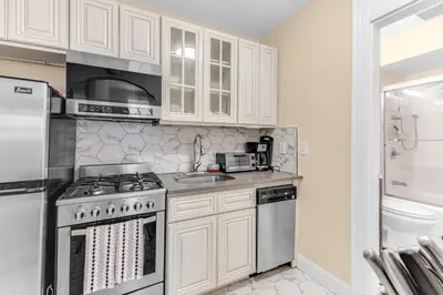 a kitchen with white cabinets and a stove top oven at Brooklyn Heights 2BR Secret Retreat in Brooklyn
