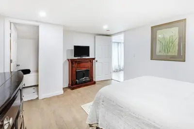 a white bedroom with a bed and a flat screen tv at Orange NJ 2BR Duplex | Walk to Train + 2BA in Orange