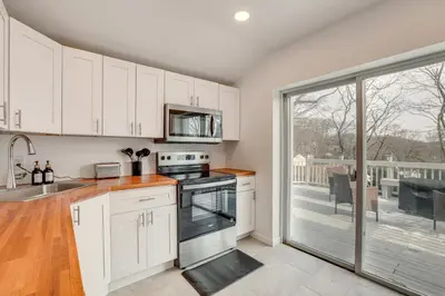a kitchen with white cabinets and a large window at Home with Lake Views and Deck in New Jersey Highlands! in Stanhope