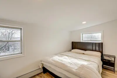 a bedroom with a bed and two windows at Home with Lake Views and Deck in New Jersey Highlands! in Stanhope