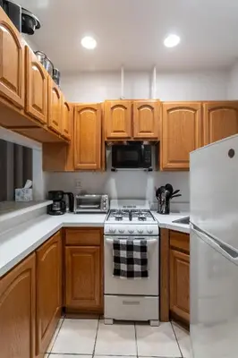 a kitchen with wooden cabinets and a white stove top oven at 2-Bedroom Apartment in Hells Kitchen - Manhattan! in New York
