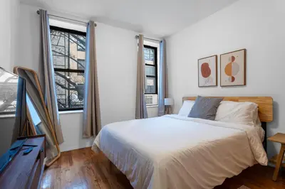 a white bedroom with a bed and two windows at 2-Bedroom Apartment in Hells Kitchen - Manhattan! in New York