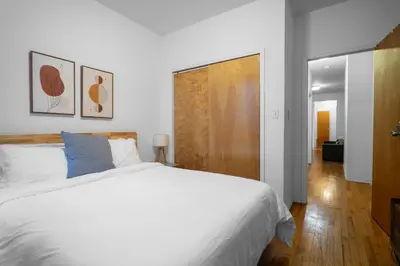 a bedroom with a white bed and a wooden door at 2-Bedroom Apartment in Hells Kitchen - Manhattan! in New York