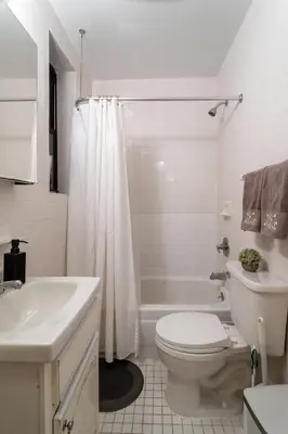 a white bathroom with a toilet and a sink at 2-Bedroom Apartment in Hells Kitchen - Manhattan! in New York