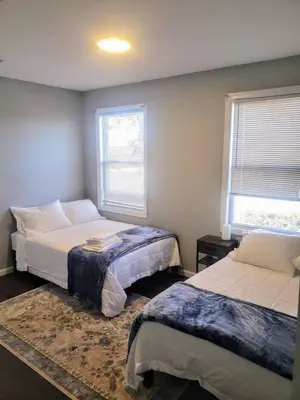 a bedroom with two beds and two windows at Attractive and Cozy Apartment - 4 bdrms 2 bths in Paterson