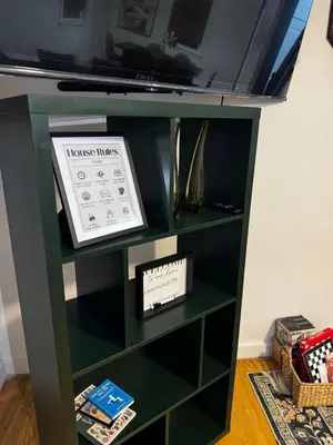 a green book shelf with a tv on top at Staten Luxe, Modern Stay Close to NJ, NYC and Brooklyn! in Arlington
