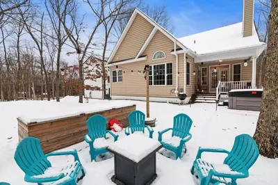 a group of chairs in the snow in front of a house at Hot Tub Game Room Spacious Close to Skiing in Albrightsville