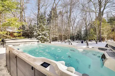 a jacuzzi tub in the snow with trees at Games, Fire Pit, Hot Tub Pocono Lake Family Home! in Pocono Lake