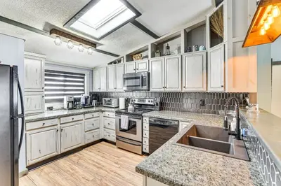 a kitchen with white cabinets and stainless steel appliances at Games, Fire Pit, Hot Tub Pocono Lake Family Home! in Pocono Lake