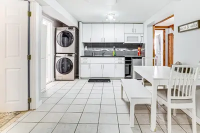 a kitchen with white cabinets and a table and appliances at Games, Fire Pit, Hot Tub Pocono Lake Family Home! in Pocono Lake