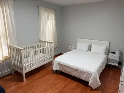 a bedroom with a crib and a white bed at Apartment 2 BR near NYC 5min from EWR & 20min from MetLife in Elizabeth