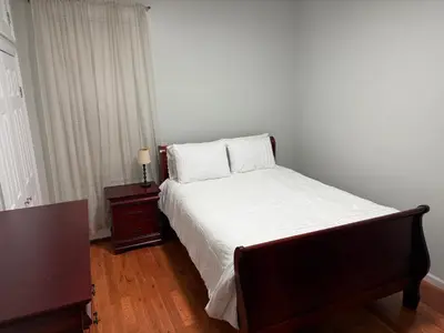 a bedroom with a bed with white sheets and a table at Apartment 2 BR near NYC 5min from EWR & 20min from MetLife in Elizabeth