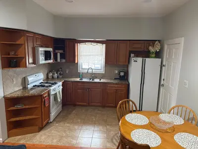a kitchen with a table and a white refrigerator at Apartment 2 BR near NYC 5min from EWR & 20min from MetLife in Elizabeth