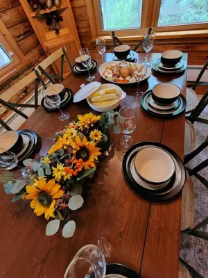 a wooden table with sunflowers and plates on it at Authentic Log Cabin Short walk to Lake & Hideout in Lake Ariel