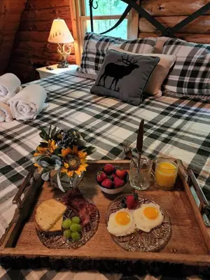a breakfast tray with eggs and fruit on a bed at Authentic Log Cabin Short walk to Lake & Hideout in Lake Ariel