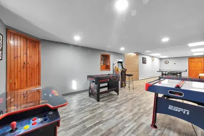 a play room with two arcade games and a table at Big Bass Hideaway with Hot Tub in Gouldsboro