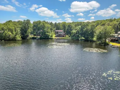 a view of a lake with a house in the distance at Lakefront Big Bass Lake Dock Games in Gouldsboro