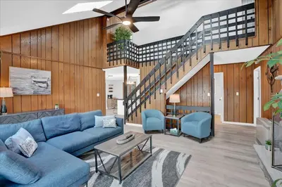 a living room with a blue couch and a staircase at Lakefront Big Bass Lake Dock Games in Gouldsboro