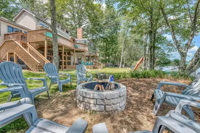 a patio with chairs and a fire pit in front of a house at Lakefront Big Bass Lake Dock Games in Gouldsboro