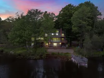 a large house on the water with lights on at Lakefront Big Bass Lake Dock Games in Gouldsboro