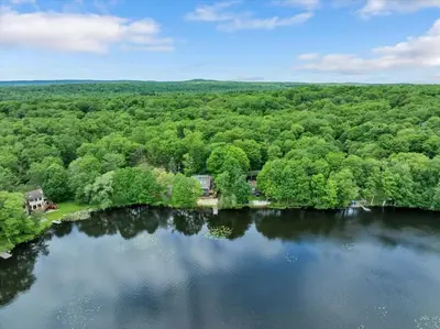 an aerial view of a lake with trees and a house at Lakefront Big Bass Lake Dock Games in Gouldsboro