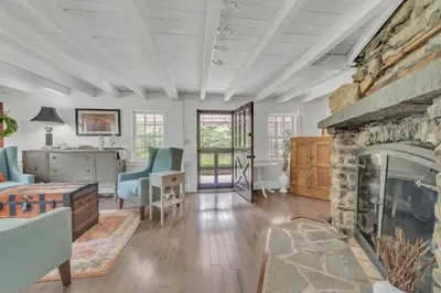 a living room with a large stone fireplace at Historic Winery Farmhouse by Lake in Hawley