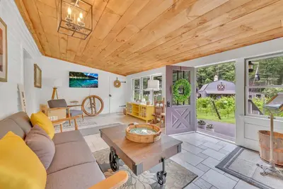 a living room with a couch and a table at Historic Winery Farmhouse by Lake in Hawley