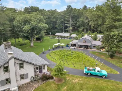 an old car driving down a road in front of a house at Historic Winery Farmhouse by Lake in Hawley