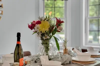 a table with a vase of flowers and a bottle of wine at Hot Tub Game Room Firepit Arrowhead Family in Thornhurst