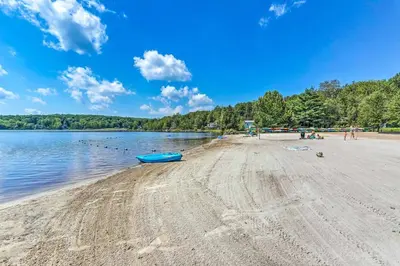 a beach with a blue boat on the water at Hot Tub Game Room Firepit Arrowhead Family in Thornhurst