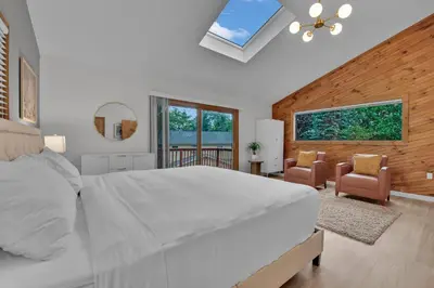 a bedroom with a large white bed and two chairs at Lakefront AC Pool Table Kayaks Refined in Tobyhanna