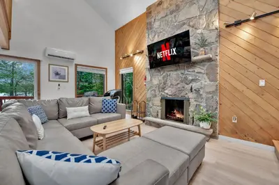 a living room with a couch and a stone fireplace at Lakefront AC Pool Table Kayaks Refined in Tobyhanna