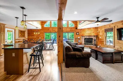 a kitchen and living room in a log home at Massive Log Chalet with Hot Tub in Lakeville