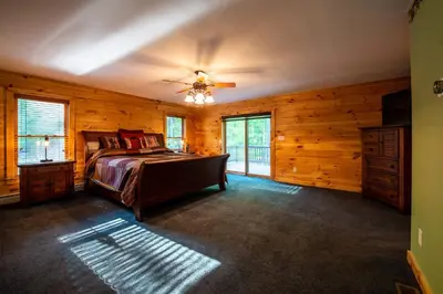 a bedroom with a bed and a ceiling fan at Massive Log Chalet with Hot Tub in Lakeville