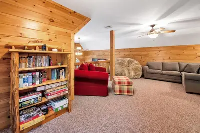 a living room with a book shelf and a couch at Massive Log Chalet with Hot Tub in Lakeville