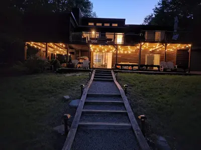 a house lit up at night with lights on it at Lakefront Hot Tub Canoes Game Room Wood FP in Gouldsboro